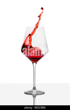 Glas Rotwein mit Spritzer auf weißer Tisch. Stockfoto