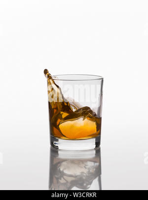 Whiskey spritzen auf elegante Glas auf weißem Hintergrund Stockfoto
