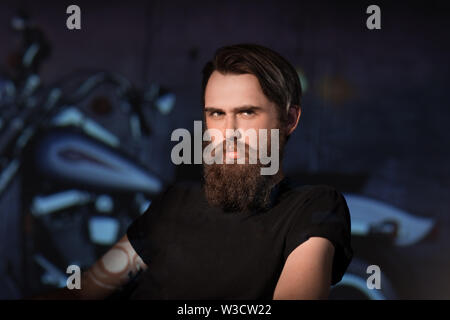 Porträt eines lächelnden Mann Biker in einem Stuhl sitzend in seinem Zimmer. Das Konzept einer Hobby Stockfoto