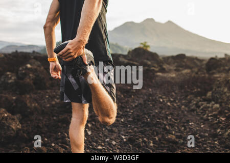 Läufer stretching Bein und Fuß und Vorbereitung für Trail Running im Freien. Aktiven und gesunden Lebensstil. Blick auf die Berge im Hintergrund. Stockfoto