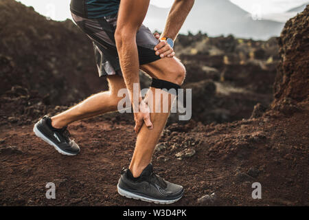 Läufer mit Knie Stützverband, haben aber ein Problem mit der Wade Muskel auf ausgeführt wird. Beinverletzung. Stockfoto