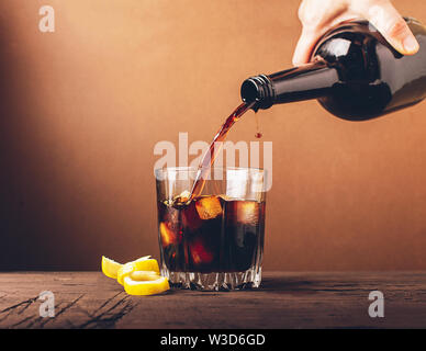 In ein Glas mit Eiswürfel gegossen Whiskey Brandy. Starke alkoholische Getränk auf einem dunklen Hintergrund. Selektive konzentrieren. Kopieren Sie Platz. Stockfoto