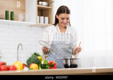 Frau rühren Suppe mit Holzlöffel, Kochen in der Küche Stockfoto