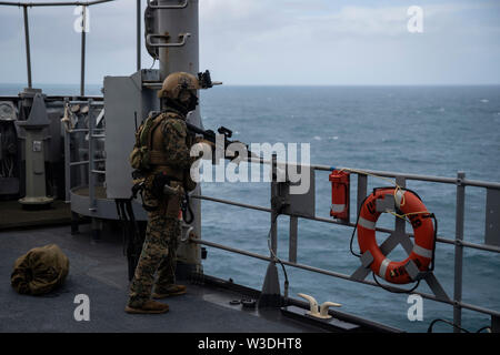 Eine Kraft, die mit der Aufklärung Marine 31 Marine Expeditionary Unit Maritime Raid-Force bietet Sicherheit bei einem Besuch, Board, Durchsuchung und Beschlagnahme Übung an Bord der Station Landung Schiff USS Ashland (LSD 48), unterwegs in der Coral Sea, 7. Juli 2019. Ashland, Teil der Wasp amphibischen bereit, Gruppe, mit Eingeschifft 31 MEU, arbeitet in der indopazifischen Region Interoperabilität mit Partnern zu verbessern und dienen als ready-Response Force für jede Art von Kontingenz, und stellen gleichzeitig eine flexible und tödliche Krise Response Force bereit, eine breite Palette von militärischen Operationen auszuführen. Stockfoto