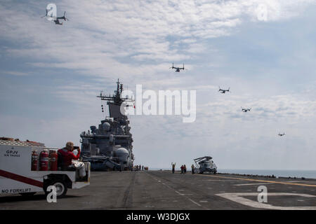 190714-N-YH 603-1271 ATLANTIK (Juli 14, 2019) MV-22 B Fischadler fliegen über die Wasp-Klasse amphibisches Schiff USS Kearsarge (LHD3). Kearsarge ist das Flaggschiff der Kearsarge Amphibious Ready Gruppe. Die kearsarge ARG ist zur Unterstützung der Maritime Security Operations eingesetzt, Krisenbewältigung und Theater Sicherheit Zusammenarbeit, während gleichzeitig ein Vorwärts naval Präsenz. (U.S. Marine Foto von Mass Communication Specialist 2. Klasse Casey Moore/Freigegeben) Stockfoto