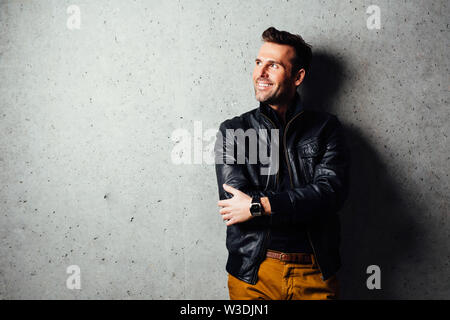 Glücklicher Mann in Leder Jacke von der Wand stehen, tragen Leder Jacke Stockfoto