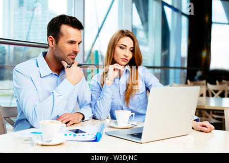Zwei Geschäftsleute sitzen in einem Büro und in diesem Notebook Stockfoto