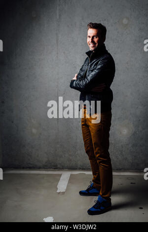 Glücklich Mann stand in der Tiefgarage aus Leder Jacke mit verschränkten Armen Stockfoto