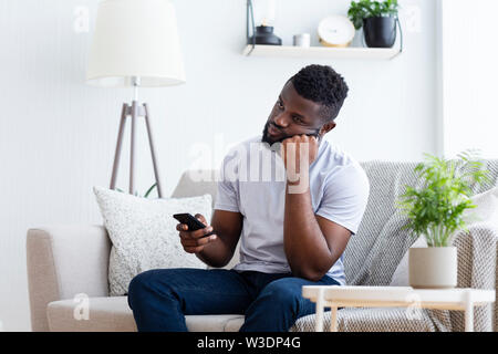 Junger Mann, Fernsehen mit Fernbedienung zum Umschalten der Sender Stockfoto