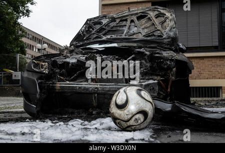 Berlin, Deutschland. Am 15. Juli 2019. Ein Fußball-Ball liegt vor einem Ausgebrannten Auto auf Guerickestraße im Berliner Bezirk Charlottenburg. In den frühen Morgenstunden insgesamt fünf Fahrzeuge gingen in Flammen auf. Die Feuerwehr konnte die Autos nicht von brennenden verhindern. Credit: Paul Zinken/dpa/Alamy leben Nachrichten Stockfoto