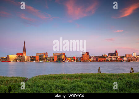 Rostock, Deutschland. Stadtbild des Rostocker Flussufers mit der Peterskirche bei Sommeruntergang. Stockfoto