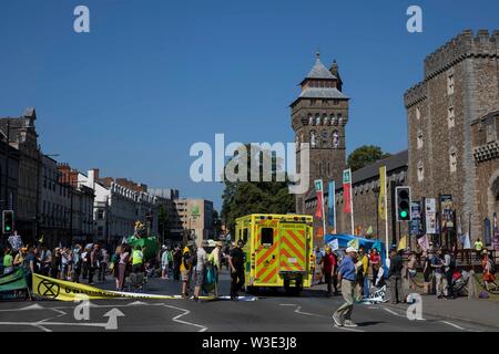 Cardiff, Wales, UK, 15. Juli 2019. Ein Krankenwagen wird durch Aktivistinnen außerhalb Cardiff Castle als Aussterben Rebellion Aktivismus erlaubt schließt Straßen rund um die Innenstadt. Aussterben Rebellion bezeichnet sich selbst als einen internationalen Rebellion gegen die strafrechtliche Untätigkeit auf das Klima und die ökologische Krise. Credit: Mark Hawkins/Alamy leben Nachrichten Stockfoto