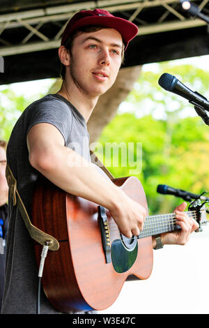 Jake Argyle, junge männliche Sänger der Ramsgate band, Argyle, auf der akustischen Gitarre vor Mikrofon im Freien an lokale Veranstaltung. Stockfoto