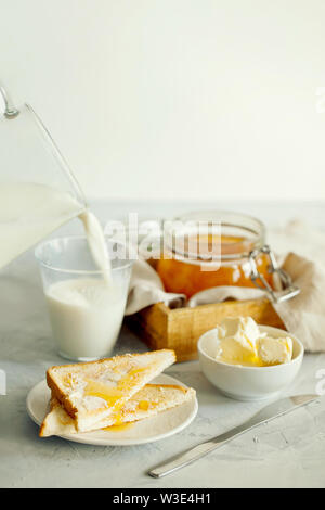 Ein Stapel von leckeren Toast mit Butter und ein Glas Milch zum Frühstück am Morgen Tabelle. Gesundes Frühstück essen Konzept. Ein elegantes Frühstück Stockfoto