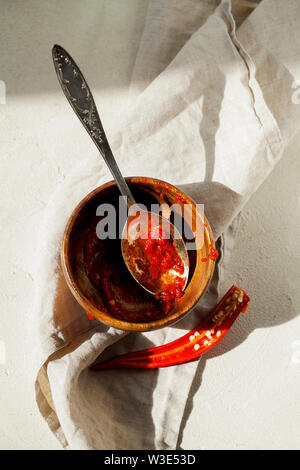 Traditionelle hausgemachte Harissa-maghrebinischen red hot chili Paste mit Knoblauch und Olivenöl in der Löffel und Schüssel Draufsicht mit Platz für Text kopieren Stockfoto