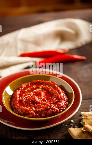 Gesunde würzig, cremig Vegetarische Vorspeise oder Snack mit gerösteter Paprika Dip mit Harissa, Pita und Oliven close-up auf hölzernen Hintergrund Stockfoto