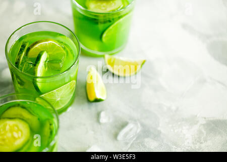 Hausgemachte trendy Eistee Matcha grüner Tee oder Limonade mit Gurke und Limone in einem Glas auf hellgrauem Hintergrund mit Kopie Raum, Ansicht von oben Stockfoto