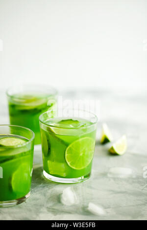 Hausgemachte trendy Eistee Matcha grüner Tee oder Limonade mit Gurke und Limone in einem Glas auf hellgrauem Hintergrund mit Platz für Text kopieren Stockfoto