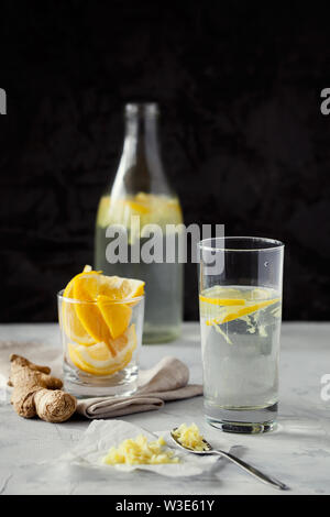 Selbstgemachte erfrischende infundiert detox Wasser oder Limonade in Glasflaschen mit geriebenem Ingwer und Zitronensaft auf dunklem Hintergrund close-up mit Platz für Text kopieren Stockfoto