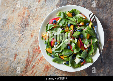 Leckeren, gesunden Salat mit frischen Mangold Blätter, Pfirsich, Blaubeeren, Stücke mit bläulich-grünen Adern auf einem weißen Teller serviert, horizontale Ansicht Stockfoto