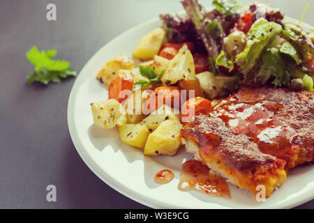 Fischfilet mit Käse überbacken mit Kartoffeln, Süßkartoffeln, Karotten und grünen und Gemüse mischen. Frisches dressing gewürzt und mit Salz bestreut Stockfoto