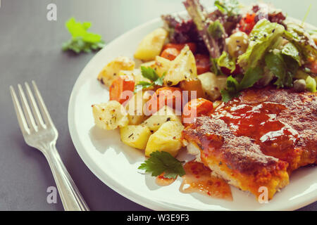 Fischfilet mit Käse überbacken mit Kartoffeln, Süßkartoffeln, Karotten und grünen und Gemüse mischen. Frisches dressing gewürzt und mit Salz bestreut Stockfoto