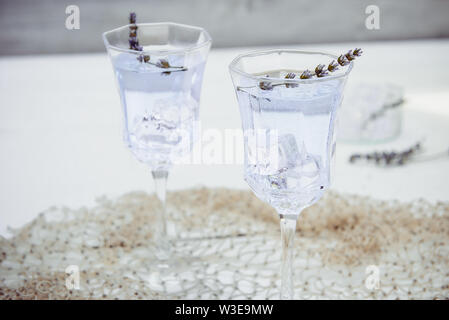 In der Nähe von frischem Lavendel Limonade mit Blumen und Eiswürfel in schönen Gläser auf weißem Holztisch. Detox Wasser. Im Sommer trinken. Ernährung Cocktail. Sele Stockfoto