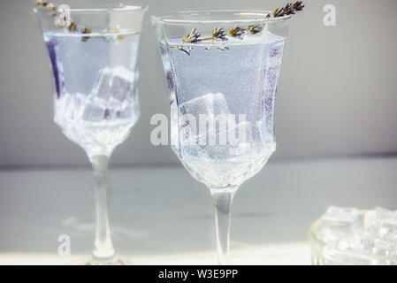 In der Nähe von frischem Lavendel Limonade mit Blumen und Eiswürfel in schönen Gläser auf weißem Holztisch. Detox Wasser. Im Sommer trinken. Ernährung Cocktail. Sele Stockfoto