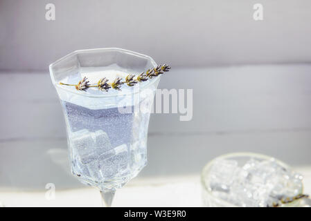 In der Nähe von frischem Lavendel Limonade mit Blumen und Eiswürfel in einem schönen Glas auf weiße Holztisch. Detox Wasser. Im Sommer trinken. Ernährung Cocktail. Wählen Sie Stockfoto