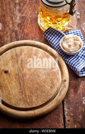 Leere alte runde Holzplatte mit Maß Bier, Serviette und Schüssel von dip auf einem alten Holz-, gesehen von oben für Essen Platzierung Stockfoto