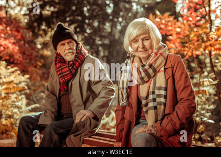 Traurige ältere Frau auf einer Bank sitzen. Stockfoto