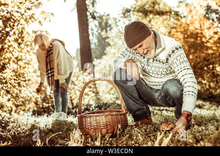 Gerne älteres Paar Pilze sammeln im Wald zusammen. Stockfoto