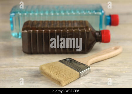 Eine Bürste liegt neben der Plastikflaschen mit Fleck und Lösungsmittel auf einem alten White vintage Holzbrett Tabelle. Für Text oder Logo. Stockfoto