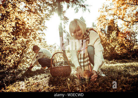 Lächelnde Frau gehen, einen grossen Pilz zu schneiden. Stockfoto