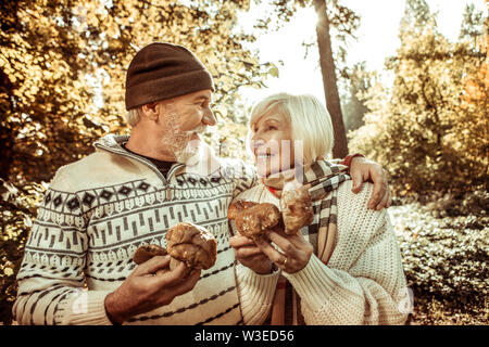 Glückliches Paar hält große Pilze und umarmen. Stockfoto