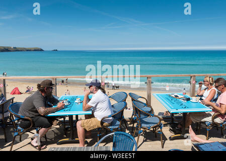 Urlauber sitzen auf der Terrasse des Fistral Beach Bar und entspannen in der Mitte Morgen Sonnenschein in Newquay in Cornwall. Stockfoto