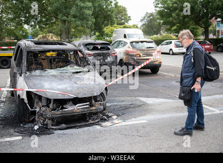 15 Juli 2019, Schleswig-Holstein, Lübeck: Jürgen Hinsch aus Hannover steht neben seinem Ausgebrannten VW Auto, das er in einem Parkhaus in der Nähe der Altstadt Insel geparkt. Er besuchte das Schleswig-Holstein Musik Festival mit seiner Frau. Unbekannte Täter mehrere Autos in Brand in der Nähe der Musik- und Kongresshalle auf Montag Nacht. Insgesamt ein Dutzend Autos verbrannt wurden oder beschädigt, sagte ein Sprecher der Feuerwehr. Die Feuerwehr geht von Brandstiftung. Wer das Feuer war zunächst unklar. Foto: Rainer Jensen/dpa Stockfoto