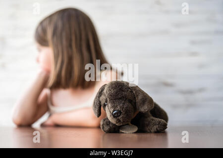 Portrait von schönen, nachdenklichen, gelangweilt kleines Mädchen mit ihr liebstes Stofftier, Tagträumen und erstellen Ideen in Ihrem Verstand. Kreativer Prozess. Soft fo Stockfoto