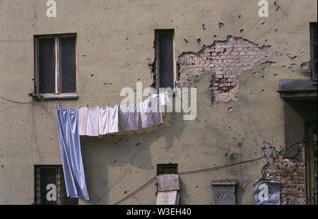 5. April 1993 während der Belagerung von Sarajevo: in Velika avlija, in der Altstadt, Wäsche abhängen auf einer Linie gegen eine Wand von ein paar Muscheln oder Mörtel Bomben geschrammt. Stockfoto