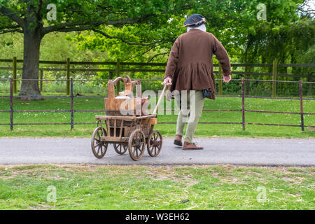 Reenactor in mittelalterlichen Kostümen ziehen mittelalterliche Getränke Warenkorb Stockfoto