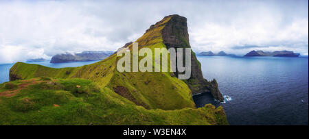 Kleine Leuchtturm in der Nähe von riesigen Felsen auf der Insel Kalsoy, Färöer Inseln Stockfoto