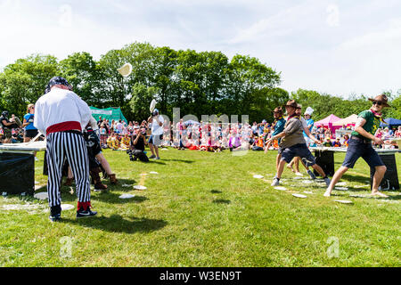 Zwei Mannschaften in Fancy Dress im Außendienst bei der Zuschauer, werfen Custard pies an einander bei der jährlichen Welt Custard Pie Meisterschaft 2019. Stockfoto