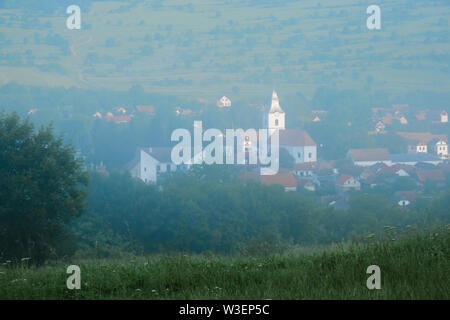 Rimetea Dorf in Siebenbürgen, Rumänien während Nebel Sonnenaufgang, als von einem erhöhten Standort auf dem nahegelegenen Hügel gesehen. Stockfoto