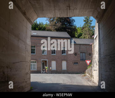 Trooz, Belgien, 4. Juli 2019: ältere Mann auf dem Fahrrad geht alte Häuser in der belgischen Stadt Trooz in der Nähe von Liege in den Ardennen Stockfoto