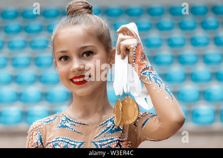 Kleine Meister, Portrait eines glücklichen Mädchen, eine Goldmedaille in der Rhythmischen Sportgymnastik den Wettbewerb gewann, große Vollendung im Kids Sport Stockfoto