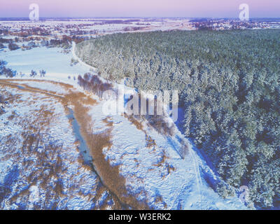 Blick von oben auf den Winter Landschaft am Abend. Felder mit Schnee bedeckt, Wald und gefrorene Creek Stockfoto