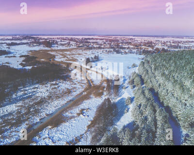 Blick von oben auf den Winter Landschaft am Abend. Felder mit Schnee bedeckt, Wald und gefrorene Creek Stockfoto