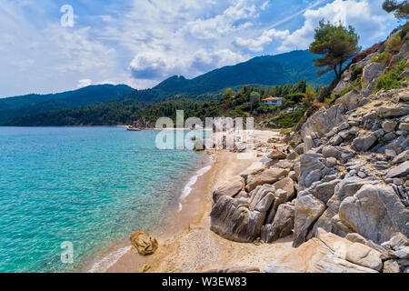 Luftaufnahme des Strandes Fava mit bunten Sonnenschirmen, Schwimmen im Meer in Vourvourou in Chalkidiki, Griechenland. Stockfoto