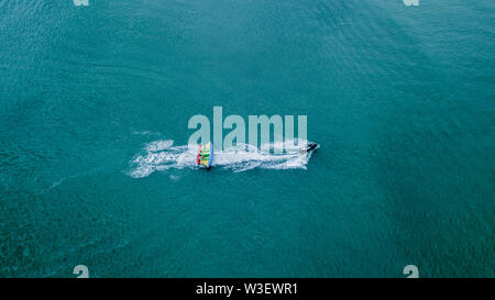 Aufblasbare Banane mit Touristen im blauen Meer. Gruppe von Menschen Reiten Banana Boot. Entfernt die Beschleunigung. Stockfoto