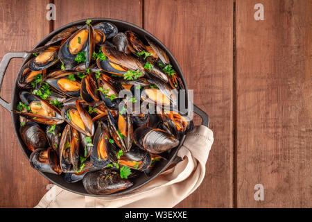 Marinara Muscheln, Moules Mariniere, in einem Kochtopf, Ansicht von oben, Schuß von oben auf einen dunklen Holzmöbeln im Landhausstil Hintergrund mit einem Platz für Text Stockfoto